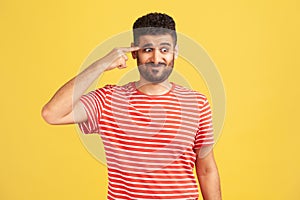 Crazy idea! Bearded man in red striped t-shirt showing stupid gesture, looking with condemnation and blaming for insane plan, dumb