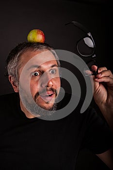 Crazy looking grumpy old man with grey beard and big glasses with apple