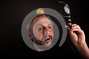 Crazy looking grumpy old man with grey beard and big glasses with apple