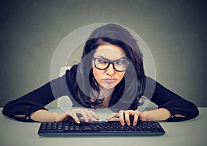 Crazy looking woman typing on the keyboard plotting a revenge