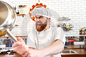 Crazy mad chef cook threatening with frying pan