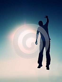 Crazy man is flying over Sun on blue sky background.