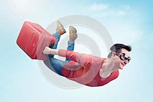 Crazy man in goggles and with red suitcase flies in the sky. Concept of vacation