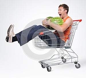 Crazy man in shopping-cart with two watermelon