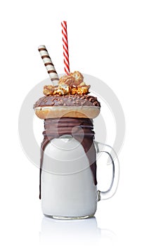 Crazy milk shake with chocolate donut, caramel popcorn and straw in glass jar