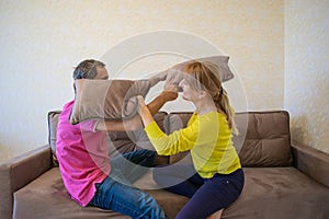 Crazy quarantine. Couple caucasian man and woman have fun quarantine at home, having fun with pillows on the sofa