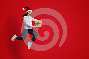 Crazy Sales. Funny Woman Wearing Santa Hat Jumping With Gift In Hands