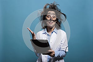 Crazy scientist with dirty face and messy hairstyle having touchscreen tablet acting shocked and mad
