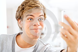 Crazy, selfie and man online with funny post to social media, website or film silly video in home. Goofy, face and weird