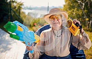 Crazy senior woman on vacation  playing with water gun