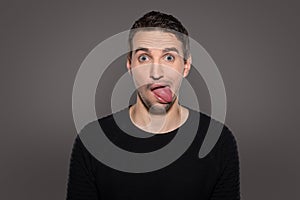 Crazy smiling man having fun while show his tongue and having a grotesque face with humor grimacing