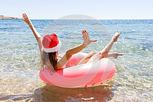 Crazy swimming with inflatable donut and christmas hat on the beach in summer sunny day