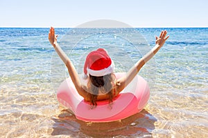 Crazy swimming with inflatable donut and christmas hat on the beach in summer sunny day