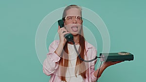 Crazy teenager girl child kid talking on wired vintage telephone of 80s, fooling making silly faces