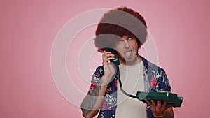 Crazy tourist hotline agent man talking on wired vintage telephone of 80s fooling making silly faces