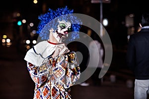 Crazy ugly grunge evil clown in town on Halloween making people shock and scared