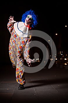 Crazy ugly grunge evil clown in town on Halloween making people shock and scared