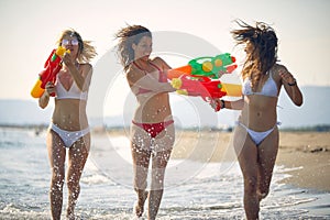 Crazy woman have fun with water gun at beach at sunny day