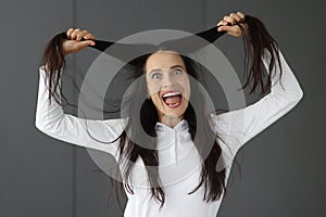 Crazy woman holds hair and makes grimaces closeup