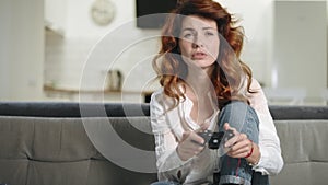 Crazy woman playing video game at home kitchen. Pretty girl holding play station