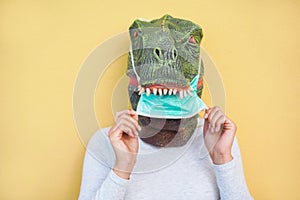 Crazy woman wearing t-rex and medical protection masks - Quarantine isolation lifestyle during coronavirus time - Absurd and funny