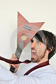 Crazy young man hiting his head with ukulele