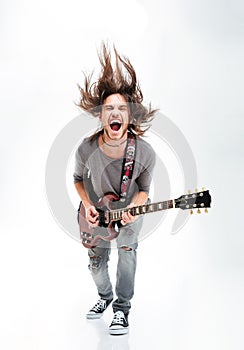 Crazy young man shaking head and playing electric guitar