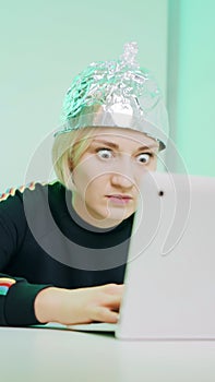 Crazy young woman with aluminum hat reacting badly on the conspiracy theory post about 5g microwaves and covid-19