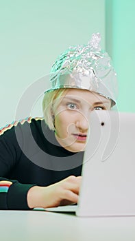 Crazy young woman with aluminum hat reacting badly on the conspiracy theory post about 5g microwaves and covid-19
