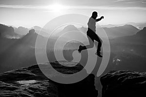 Crazyman in black jump between sharp rocks.