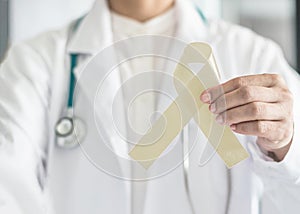 Cream awareness ribbon  in doctorÃ¢â¬â¢s hand support symbolic bow color for Degenerative Disc Disease DDD, Paralysis, SCI photo