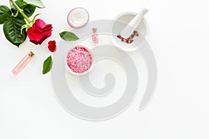 Cream, bath salt, lotion for organic cosmetics with rose flower on white background top view space for text