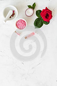 Cream, bath salt, lotion for organic cosmetics with rose flower on white marble background top view space for text