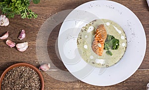 Cream of broccoli soup with salmon top view a wooden background