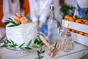 Cream cake decorated with fresh tangerines and leaves at a themed party