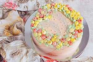 Cream cake decorated with small yellow and pink roses