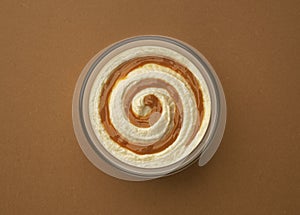 Cream cheese with caramel cream swirl on brown background, top view