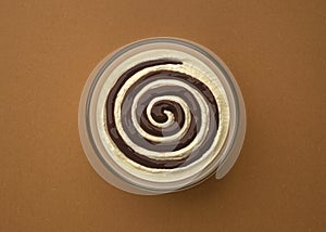 Cream cheese with chocolate cream swirl on brown background, top view