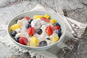 Cream cheese salad with strawberries, blueberries, pineapple close-up in a bowl. Horizontal