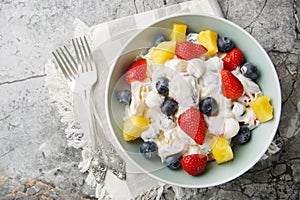 Cream cheese salad with strawberries, blueberries, pineapple close-up in a bowl. Horizontal top view
