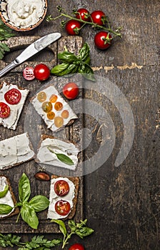 Cream cheese sandwich with seasoning and tomatoes on rustic wooden background, top view, border, vertical. Healthy, diet or
