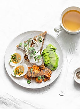 Cream cheese toast, avocado, boiled egg, baked sweet potatoes - delicious healthy breakfast or snack on a light background