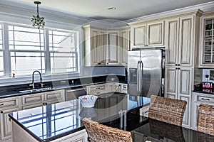 A cream colored new construction kitchen with black granite countertops and wood flooring and stainless steel appliances