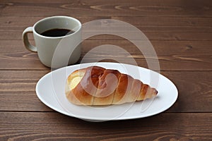 cream cornet roll bread and hot coffee on plate isolated on table