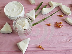 Cream cosmetic, coconut on a pink wooden background, capsules