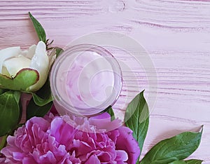 Cream cosmetic peony flower on a pink wooden