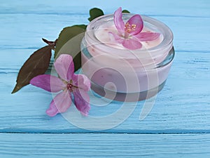 Cream cosmetic lotion freshness glass essence magnolia handmade pink flowers on blue wooden