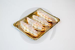 Cream croissants in a gold tray on white background