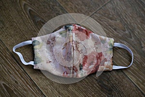 Cream fabric mask with a floral pattern on a dark background. protection from the Covid-19 virus