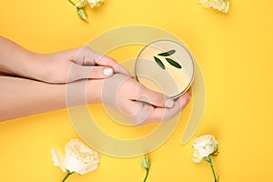 Cream in hands on a yellow background. Hand of a young woman holding and showing a can of cream on a bright yellow table. Bright